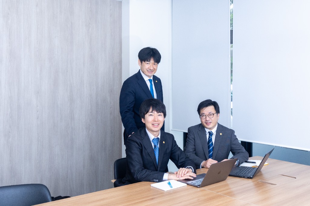 会議室でノートPCを囲み打ち合わせをするコンサルタントチーム